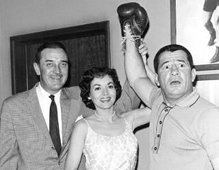  Star Lee Bowman en pretty Jil Jarmyn raise Rocky Graziano's mitt in victory as his pugilistic prowess convinces some dirty gamblers to return the jewels they conned out of a wealthy matron in the episode "Triple Cross" on "Miami Undercover", March 8. 1961