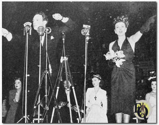 Paulette Goddard auctions off her orchid corsage with William Gargan calling the bids at the War Bond Rally in Madison Square Garden (September 1942).