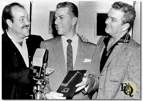 Gunsmoke is an American radio and television Western drama series created by director Norman Macdonnell (R) and writer John Meston. The stories take place in and around Dodge City, Kansas, during the settlement of the American West. The central character is lawman Marshal Matt Dillon, played by William Conrad (L) on radio and James Arness on television. Rex Koury (center) composed the theme. He's seen here receive the "Bud Shank Flute" the DownBeat magazine award. (Feb 2. 1957)
