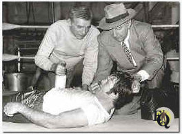 POISONED PUNCH -- Manager Sam Hatter (Dane Clark, l.) and Doc Hatter (Lloyd Nolan) vainly try to revive Kid Hogan (heavyweight boxer Jerry Quarry) after a sparring match, in "The Sunday Punch" on the NBC Television network colorcast Sunday, Jan. 11 (8-9 p.m. NYT) 1976. 